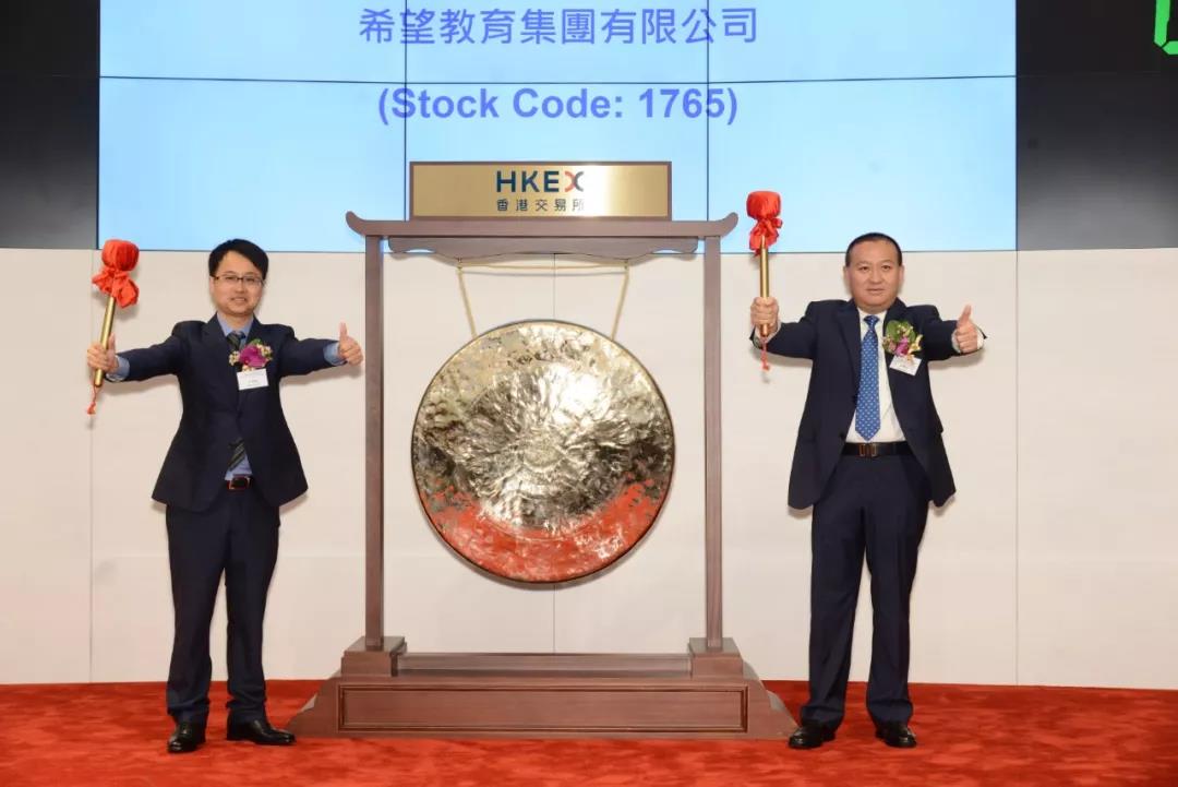 图为:王德根先生,汪辉武先生共同敲响香港联交所上市铜锣